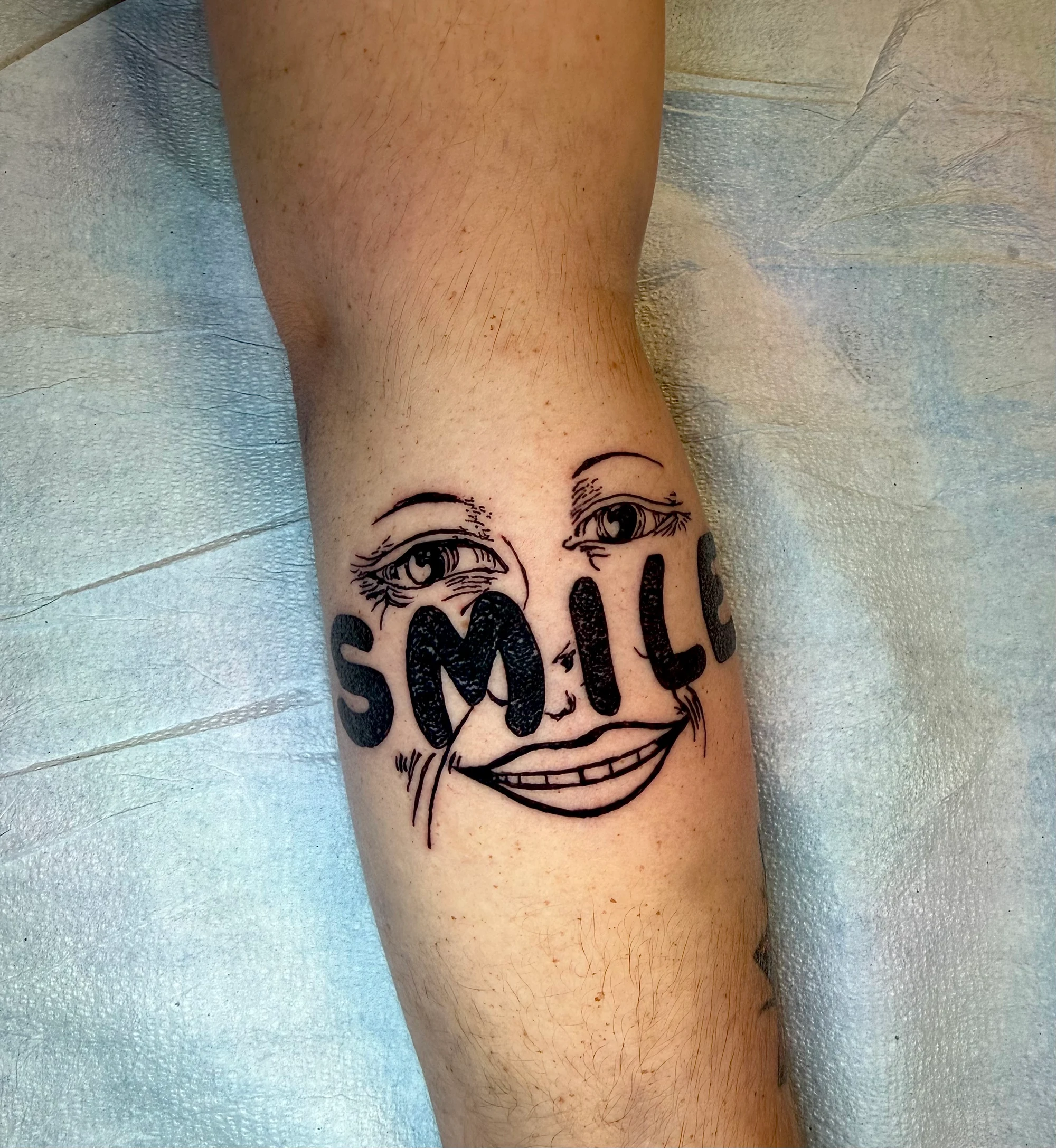 Traditional “smile” face tattoo on calf